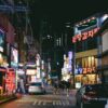 a busy city street at night with neon signs