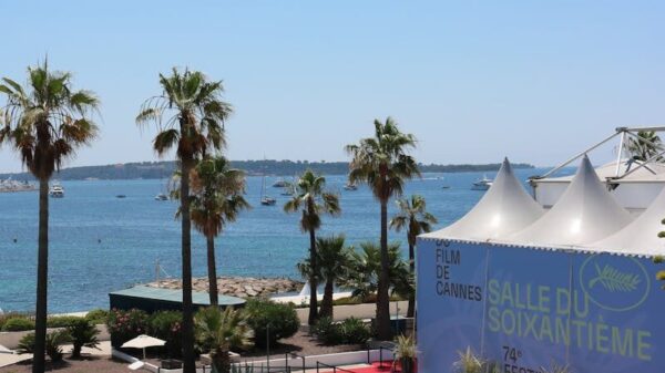 A scenic view of Cannes Film Festival tents with a backdrop of the sea and palm trees.