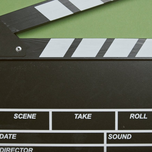 A classic film clapperboard on a green surface, essential for movie scenes.