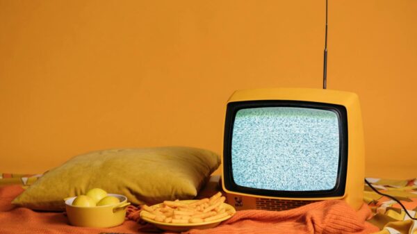 A vintage yellow TV with static, surrounded by fries, apples, and a cozy pillow setup.