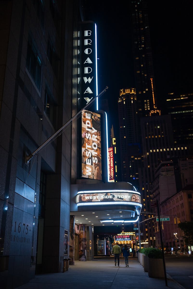 A vibrant night view of Broadway Theater in New York City featuring West Side Story signage.