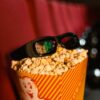 Close-up of popcorn and 3D glasses on cinema seats, ready for a movie experience.