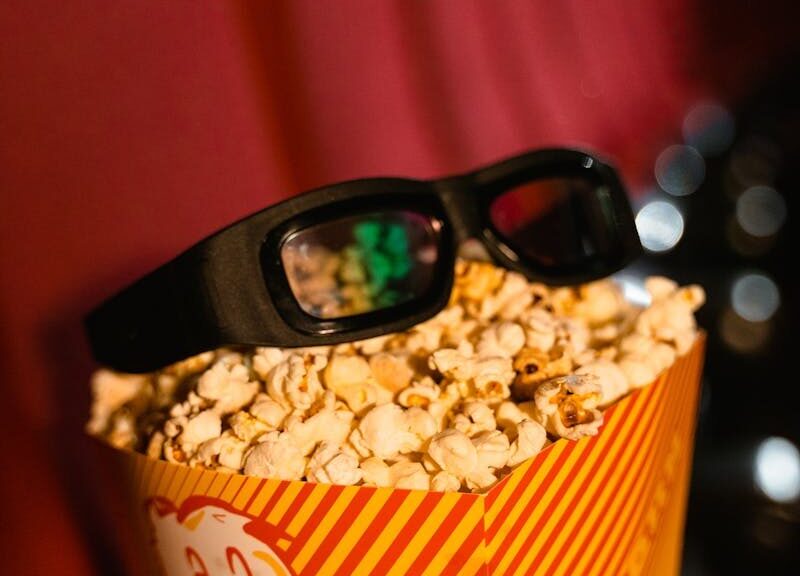 Close-up of popcorn and 3D glasses on cinema seats, ready for a movie experience.