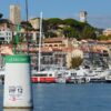Picturesque Cannes harbor with luxury yachts and historic architecture on a sunny day.