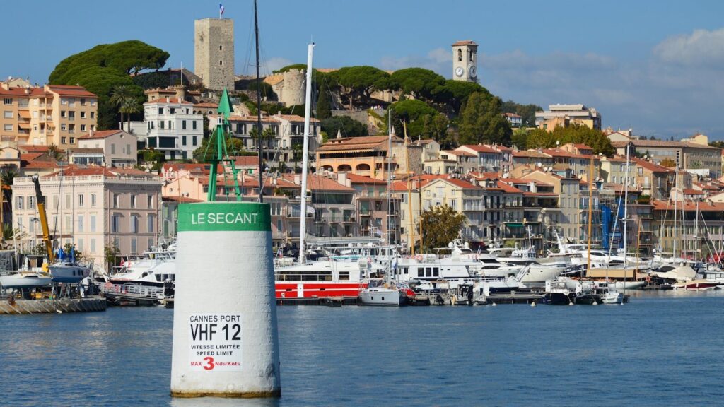 Picturesque Cannes harbor with luxury yachts and historic architecture on a sunny day.