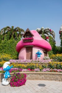 Vibrant Smurf-themed garden display with mushroom houses in Dubai's Miracle Garden, a popular family attraction.
