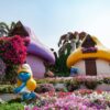 Colorful Smurf-themed garden with vibrant flowers at Dubai Miracle Garden, ideal travel spot.