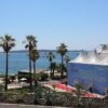 A scenic view of Cannes Film Festival tents with a backdrop of the sea and palm trees.