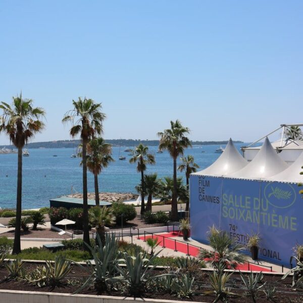 A scenic view of Cannes Film Festival tents with a backdrop of the sea and palm trees.
