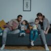 A family shares bonding time with popcorn on the sofa during movie night.