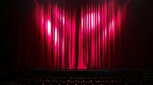 Empty theater stage with red curtains and seating, ready for a performance.