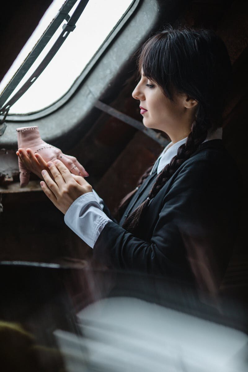Profile of a woman in braided hair, classic costume, beside window.