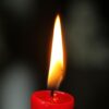 A detailed close-up of a single red candle flame glowing against a dark background, highlighting warmth and serenity.