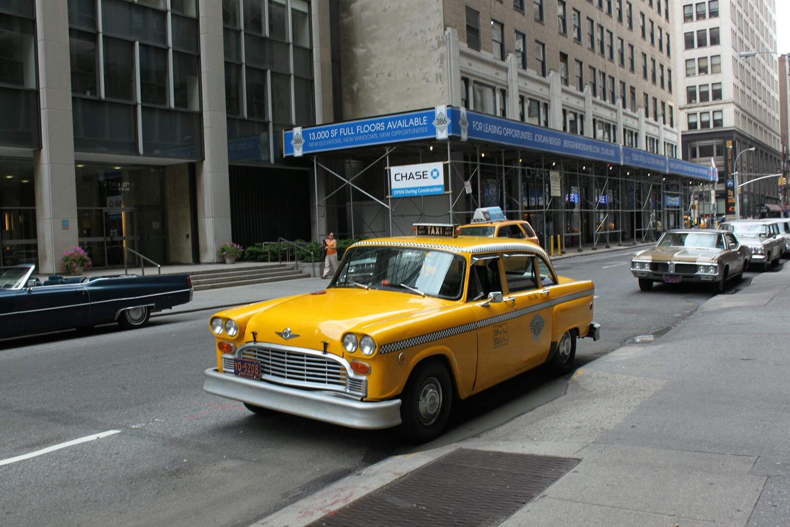 Vintage yellow taxi cab parked on a bustling New York City street.
