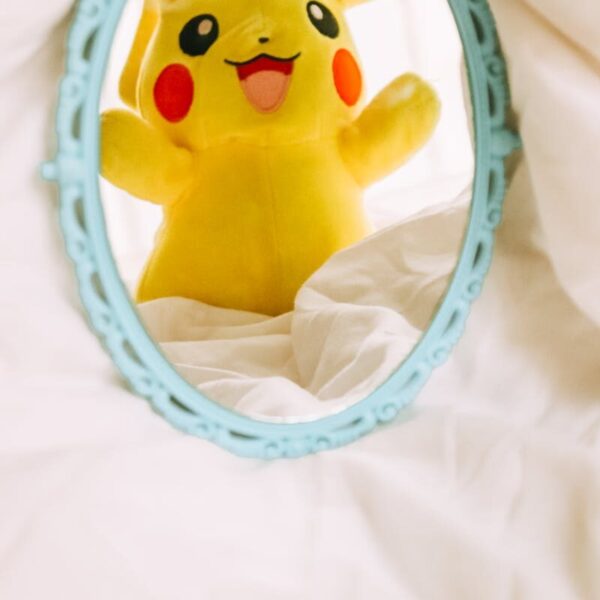 Adorable Pikachu plush reflected in a vintage mirror, adding a playful touch to decor.