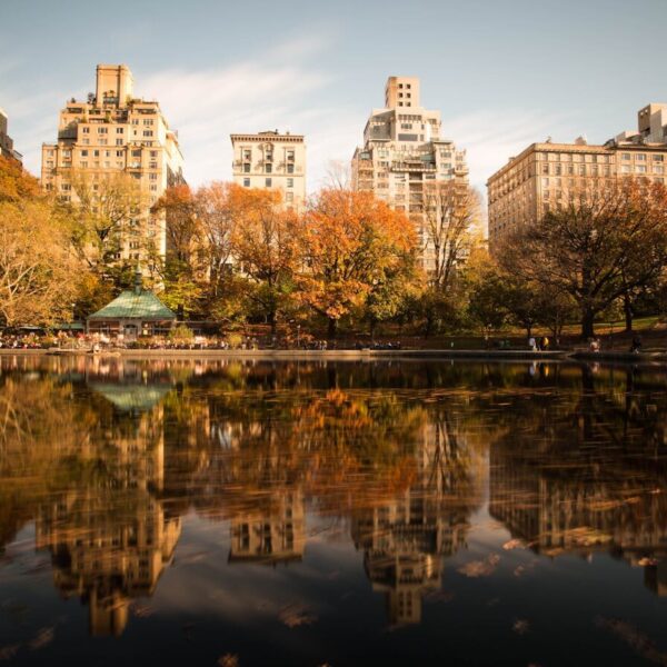 Stunning autumn view of Central Park with cityscape reflecting in the lake.