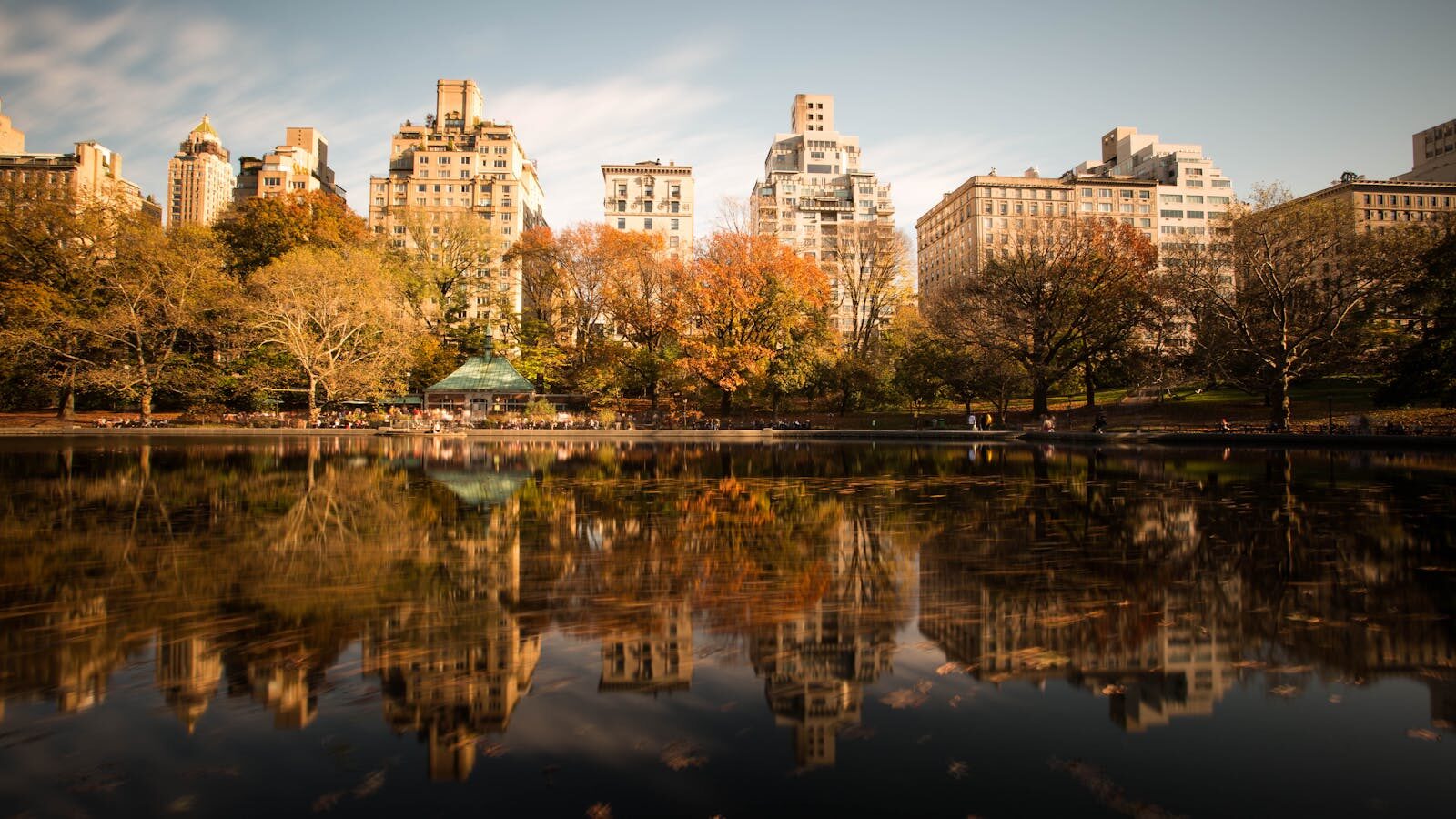 Stunning autumn view of Central Park with cityscape reflecting in the lake.