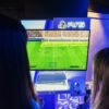 Two gamers playing FIFA on PS5 at a nighttime gaming event.