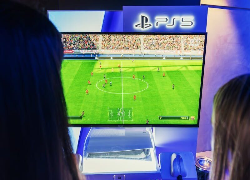 Two gamers playing FIFA on PS5 at a nighttime gaming event.