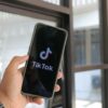 Close-up of a hand holding a smartphone displaying the TikTok app indoors.