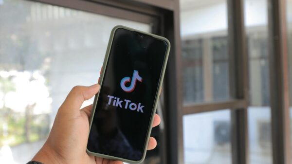 Close-up of a hand holding a smartphone displaying the TikTok app indoors.