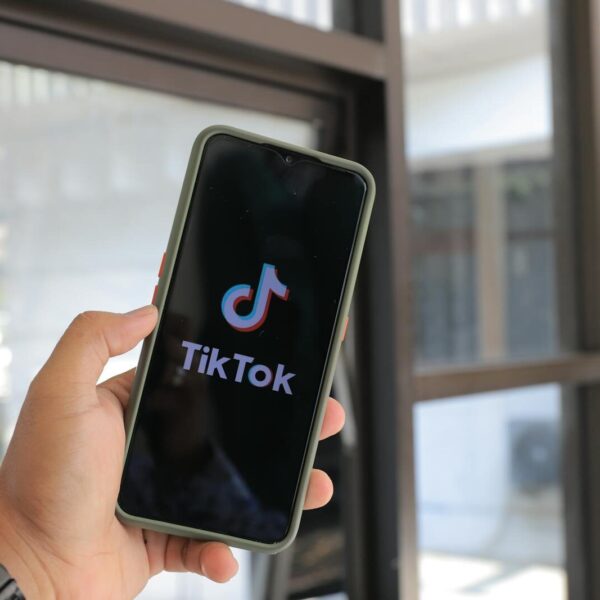 Close-up of a hand holding a smartphone displaying the TikTok app indoors.