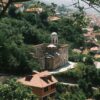 A picturesque view of a historic church in Prizren, Kosovo, amidst lush summer greenery.