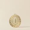 Close-up of a gold medal with number one on beige background, symbolizing victory.