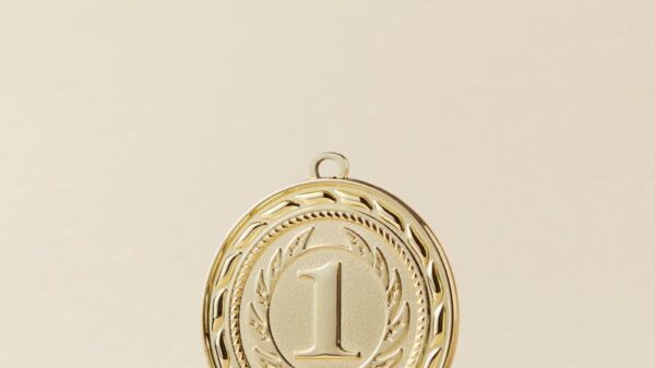 Close-up of a gold medal with number one on beige background, symbolizing victory.