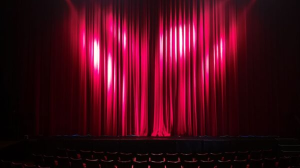 Empty theater stage with red curtains and seating, ready for a performance.