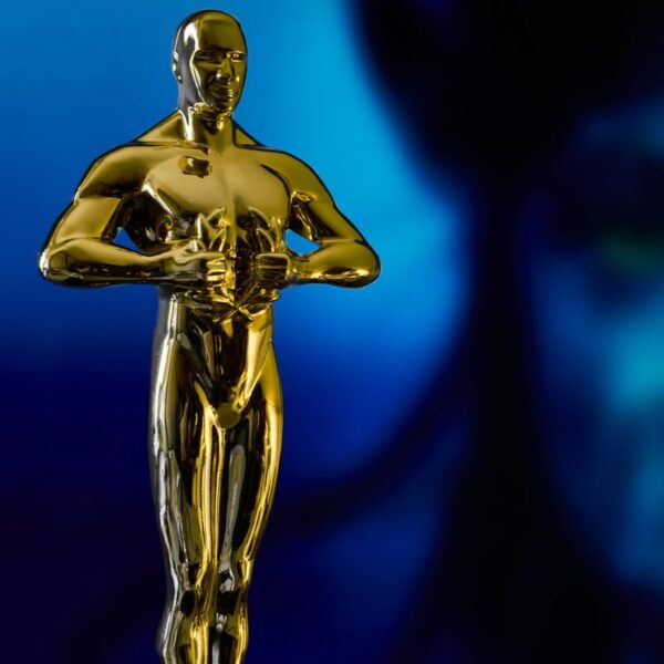 A shining Oscar statuette, symbolizing achievement in the film industry, against a vibrant blue backdrop.