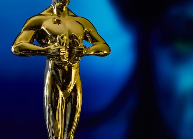 A shining Oscar statuette, symbolizing achievement in the film industry, against a vibrant blue backdrop.
