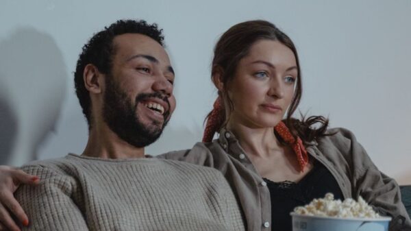 Smiling couple enjoying a cozy evening with popcorn and TV. Ideal for lifestyles imagery.