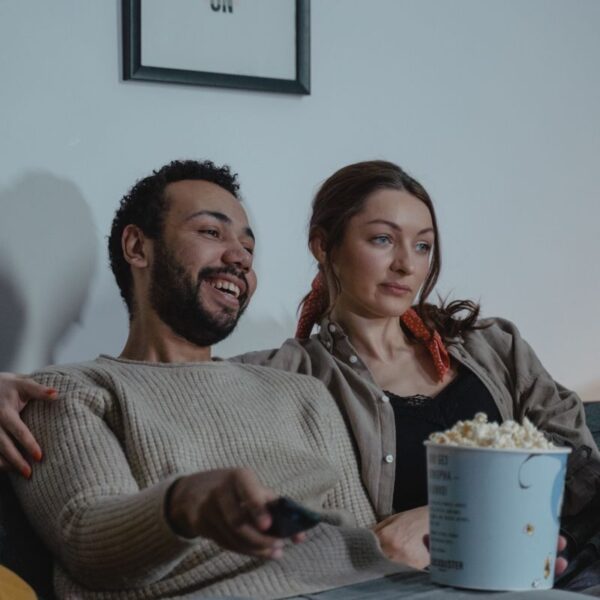 Smiling couple enjoying a cozy evening with popcorn and TV. Ideal for lifestyles imagery.