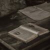 A pile of vintage open books on a rustic wooden table in a cozy indoor setting.