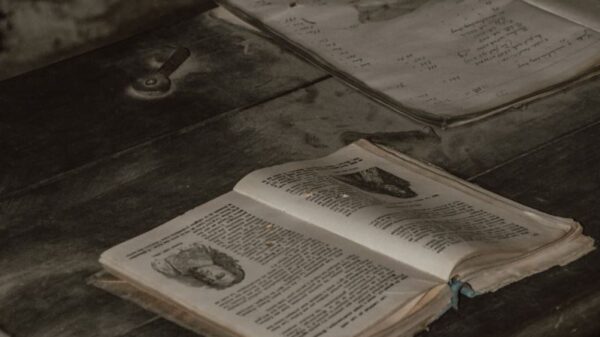 A pile of vintage open books on a rustic wooden table in a cozy indoor setting.