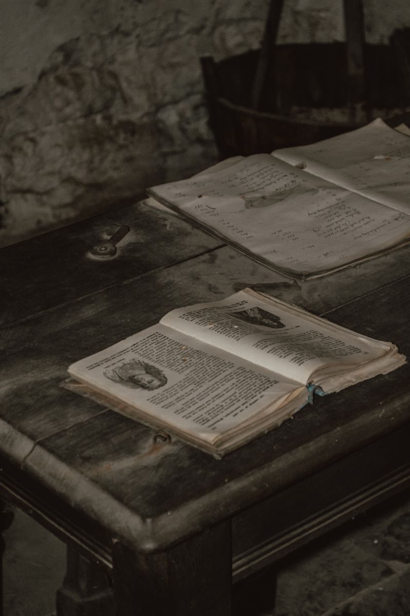 A pile of vintage open books on a rustic wooden table in a cozy indoor setting.