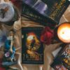 A cozy arrangement featuring fantasy novels, glowing candles, and decorative roses.