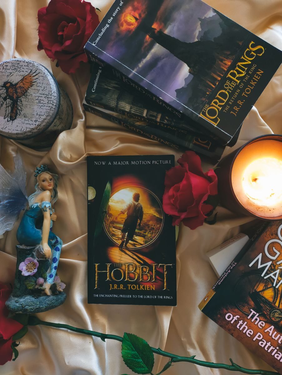A cozy arrangement featuring fantasy novels, glowing candles, and decorative roses.