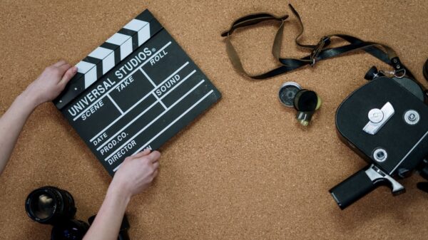 Top view of classic filmmaking tools including a slate and vintage camera on a cork surface.