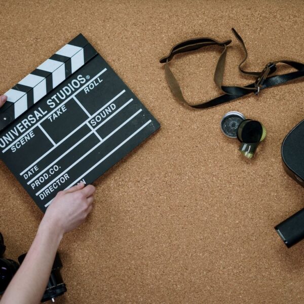 Top view of classic filmmaking tools including a slate and vintage camera on a cork surface.