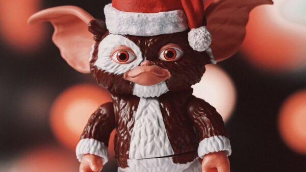 A whimsical toy figurine wearing a Santa hat against a festive bokeh background.