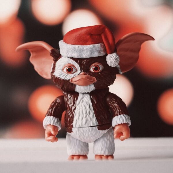 A whimsical toy figurine wearing a Santa hat against a festive bokeh background.