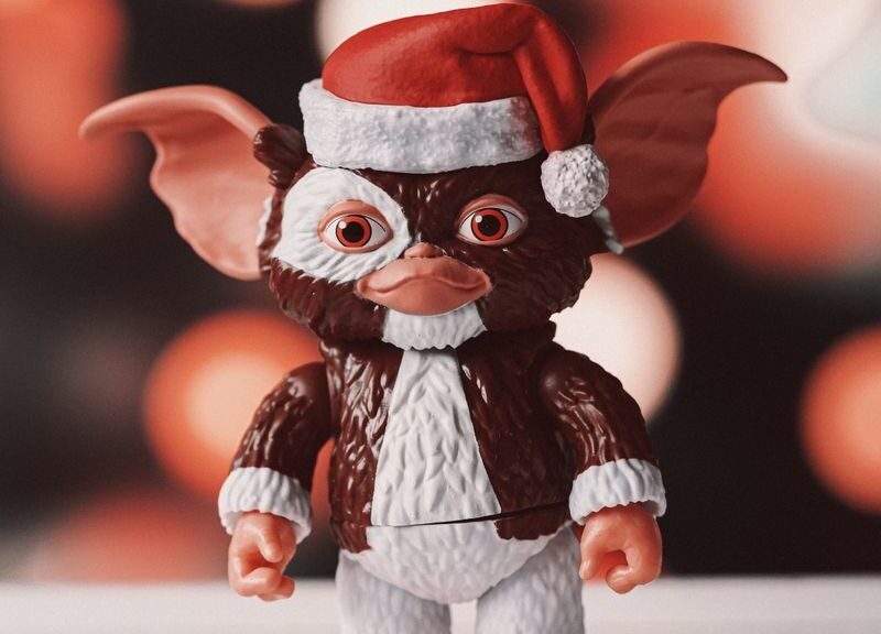 A whimsical toy figurine wearing a Santa hat against a festive bokeh background.