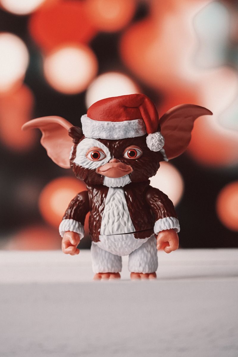A whimsical toy figurine wearing a Santa hat against a festive bokeh background.