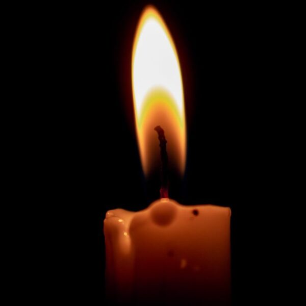 A burning candle casting a warm glow in the dark, highlighting serenity and calmness.