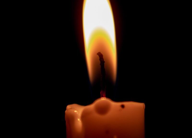 A burning candle casting a warm glow in the dark, highlighting serenity and calmness.