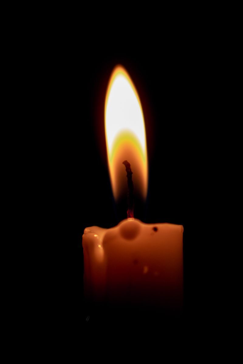 A burning candle casting a warm glow in the dark, highlighting serenity and calmness.