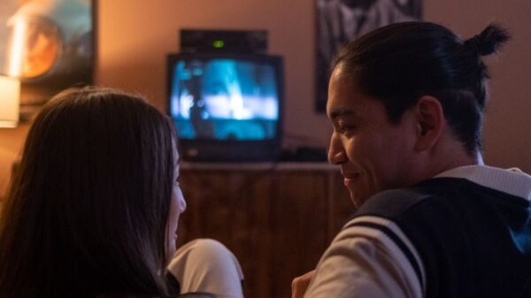 A couple enjoys a cozy movie night at home, watching TV on a couch in dim lighting.