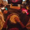 Person enjoying popcorn while watching Stranger Things in a cozy room setup.